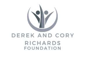 The logo features two abstract human figures with arms raised, encircled by a curved line forming a semi-circle above them. Below the image, in uppercase letters, are the words "DEREK AND CORY RICHARDS FOUNDATION." The monochromatic gray color scheme adds to its sleek and auto draft-inspired design.